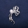 Reduzierte Brosche in Schleifenform mit einer Perle, weiß, 50×30 mm, silberfarbenes Metall